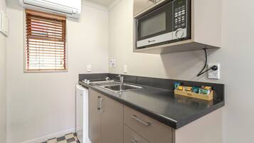 A compact kitchen with a built-in microwave, a sink, and a compact refrigerator.