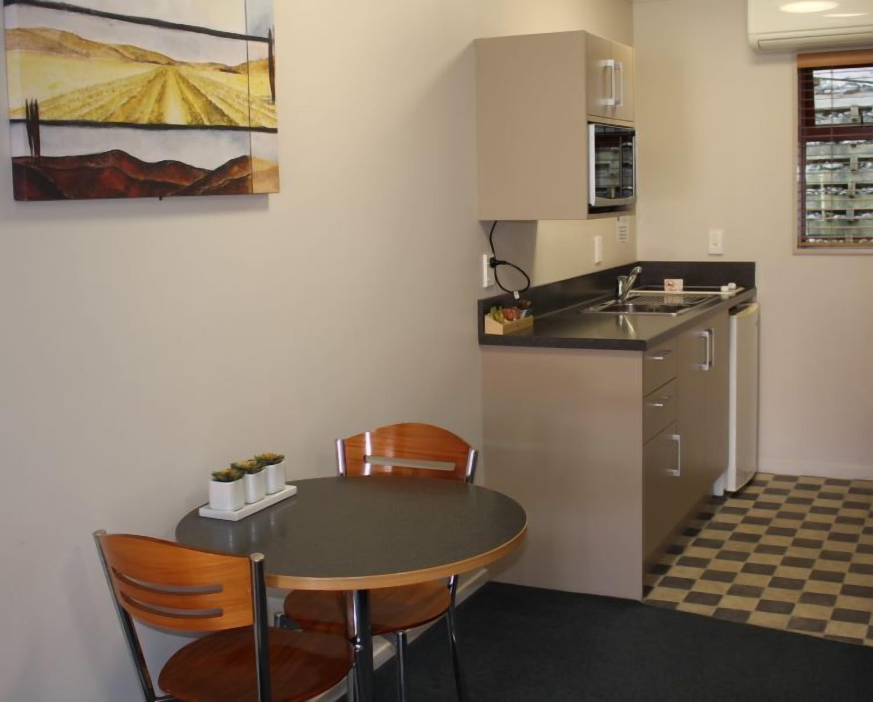Una cocina compacta con comedor, refrigerador, microondas y piso a cuadros.