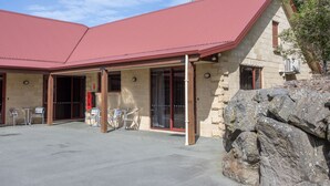 Un edificio con techo rojo, paredes de piedra y un patio cubierto con sillas de metal.