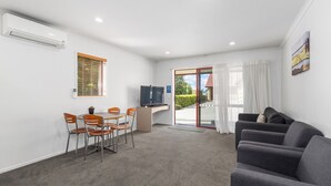 Una habitación moderna con zona de comedor, televisión de pantalla plana y sofá.