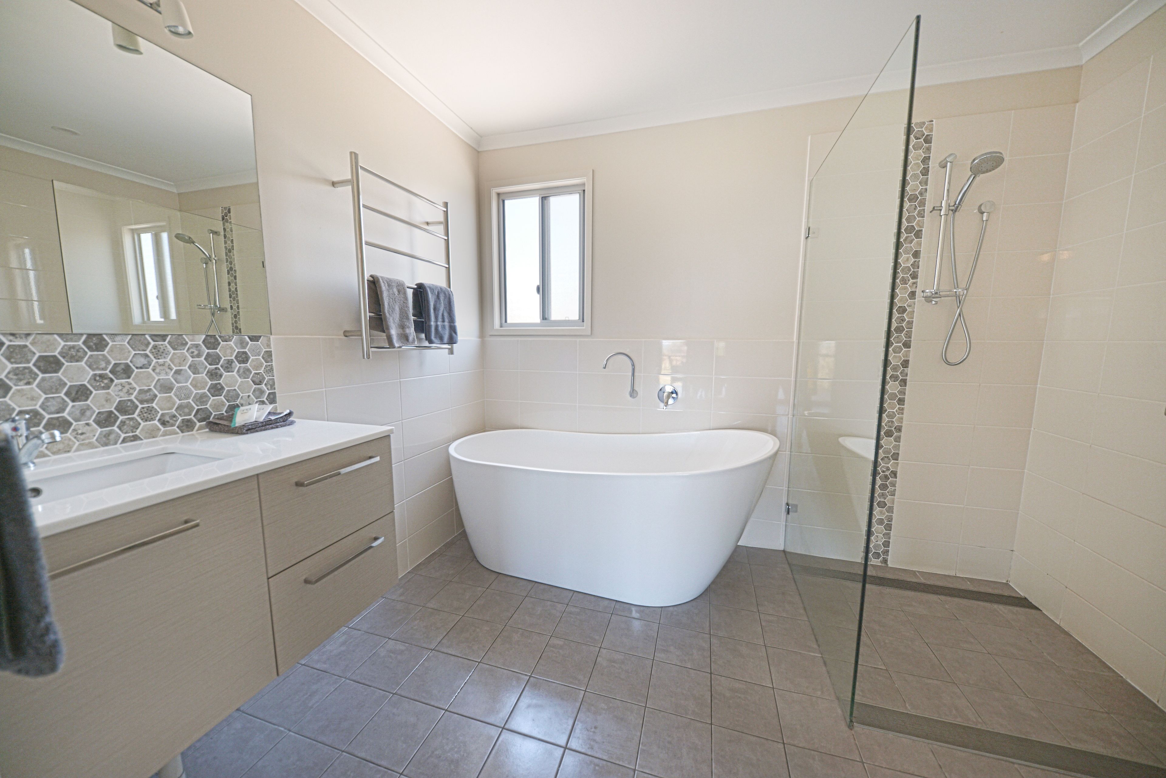 Een moderne badkamer met een vrijstaand bad, een douchecabine met glazen wanden en een grote spiegel.