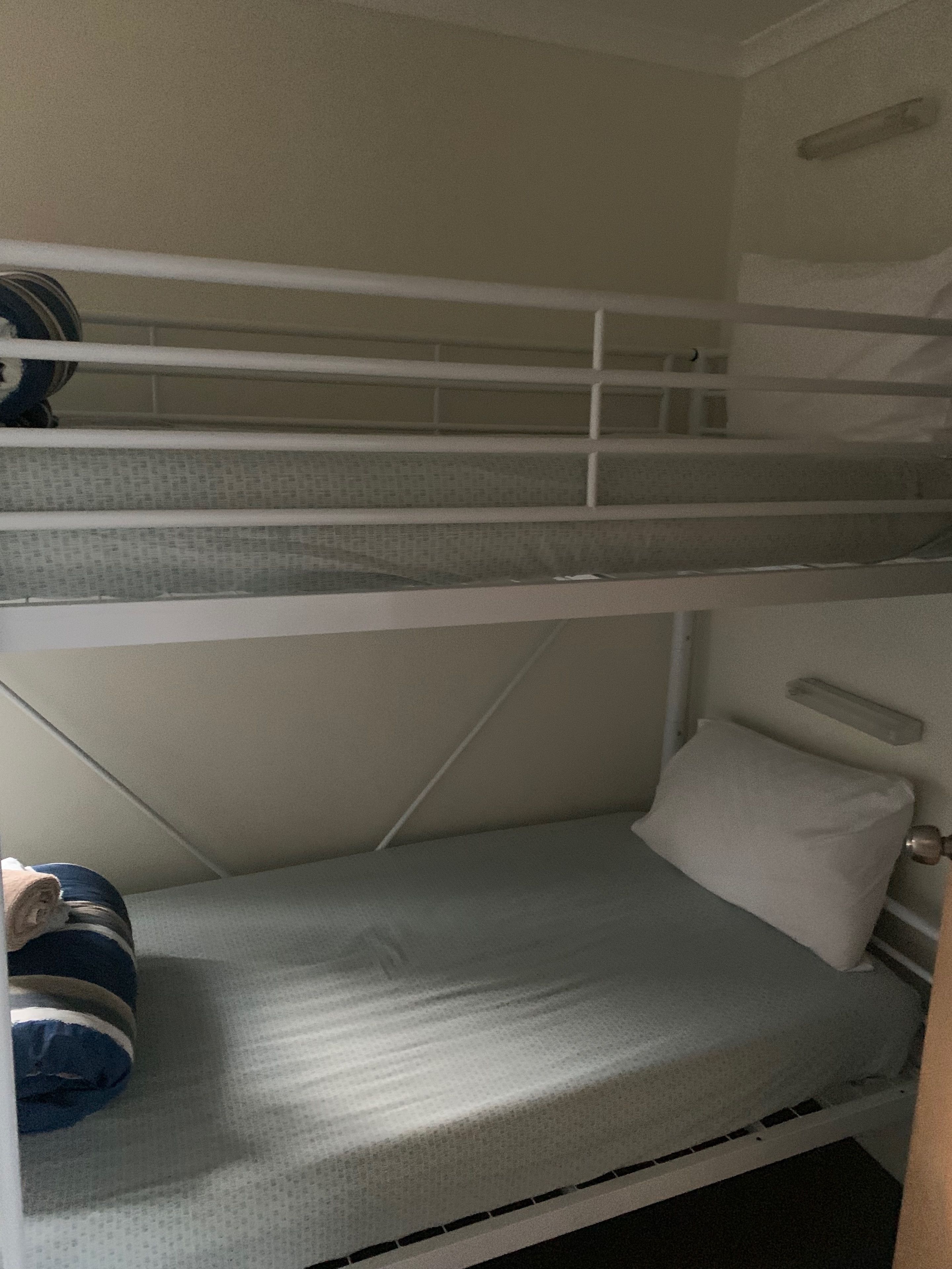 Ein Mehrbettzimmer mit Matratze, Kopfkissen und zusammengerollter Kleidung in der unteren Etage.