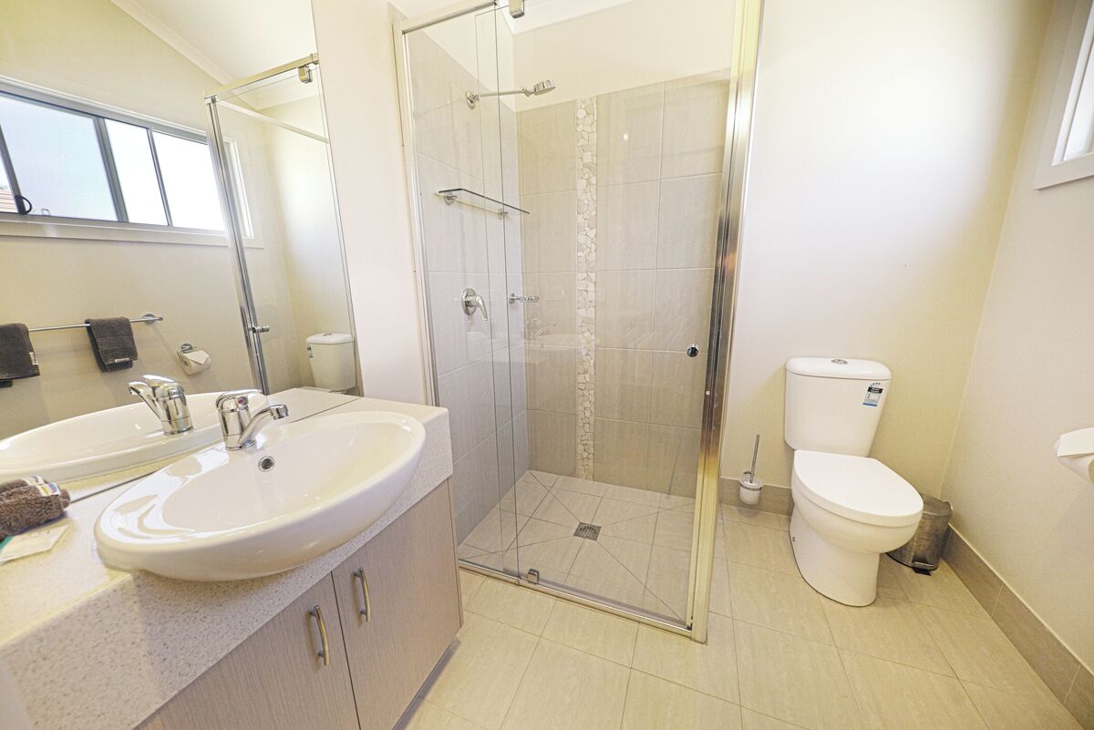 Un baño moderno con cabina de ducha de vidrio, tocador doble y un inodoro.