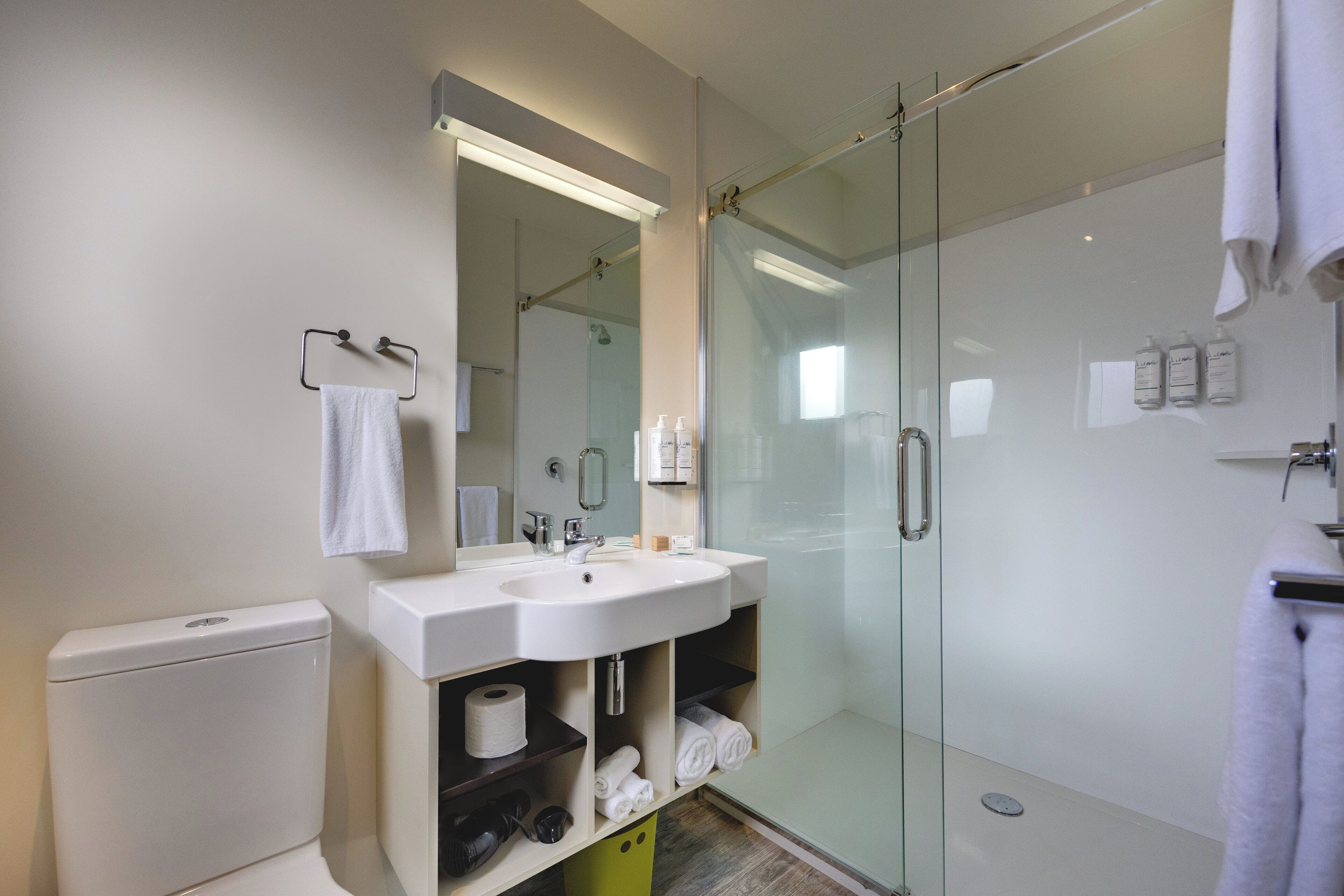 A modern bathroom with a glass-enclosed shower, a white sink, and a toilet.