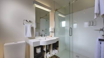 A modern bathroom with a glass-enclosed shower, a white sink, and a toilet.