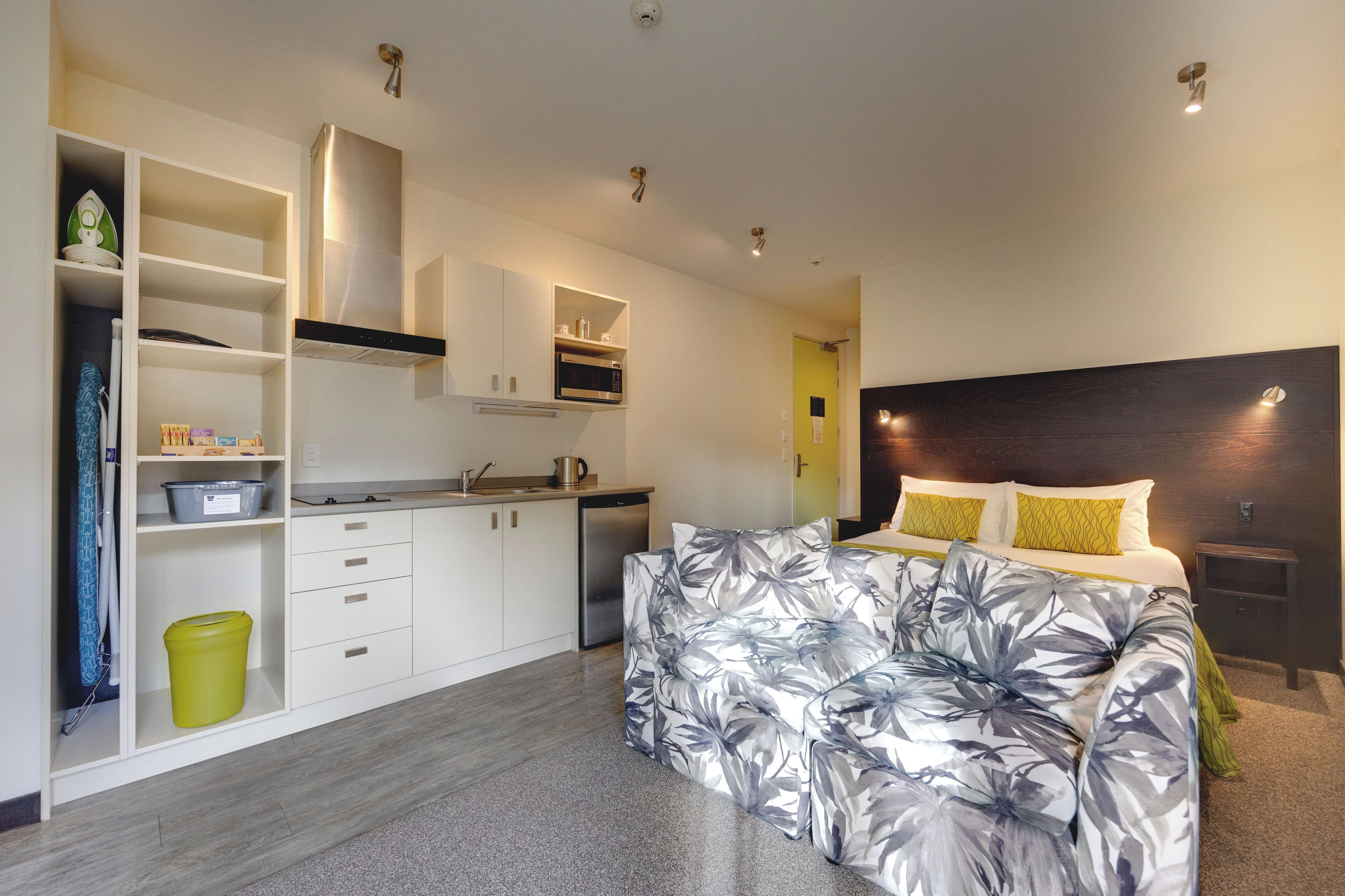 Une chambre moderne dotée d’un grand lit, d’une armoire intégrée, d’un coin cuisine et d’une salle de bain.