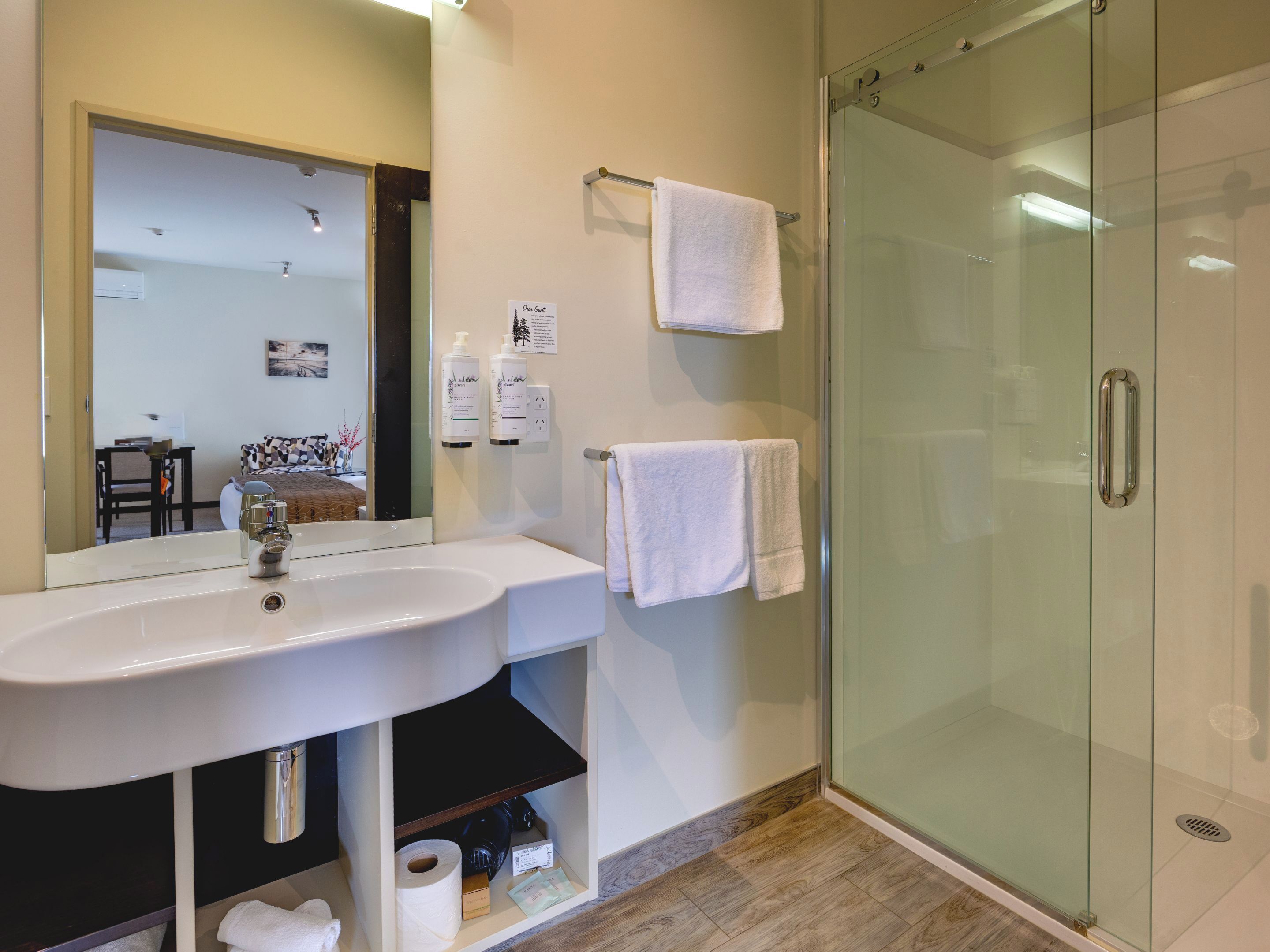 A modern bathroom with a glass shower enclosure, a white sink, and a mirror.