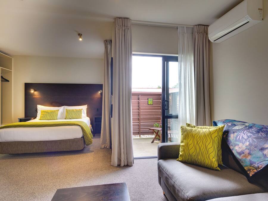 Una habitación de hotel con cama, sofá, mesa de centro y aire acondicionado.