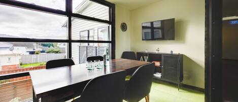 Una sala de conferencias con una gran mesa, cuatro sillas, un reloj y un televisor instalado en la pared.