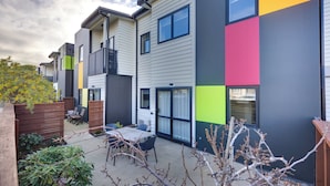 A modern apartment building with a patio area featuring a table and chairs. - Ava Lodge (Lower Hutt)