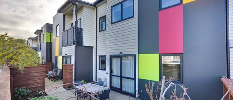 A modern apartment building with a patio area featuring a table and chairs.