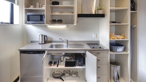 A compact kitchen with built-in appliances, open shelving, and a dishwasher. - Ava Lodge (Lower Hutt)