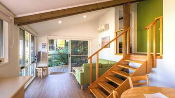 A modern interior with a wooden staircase, a green sofa, and a dining area.
