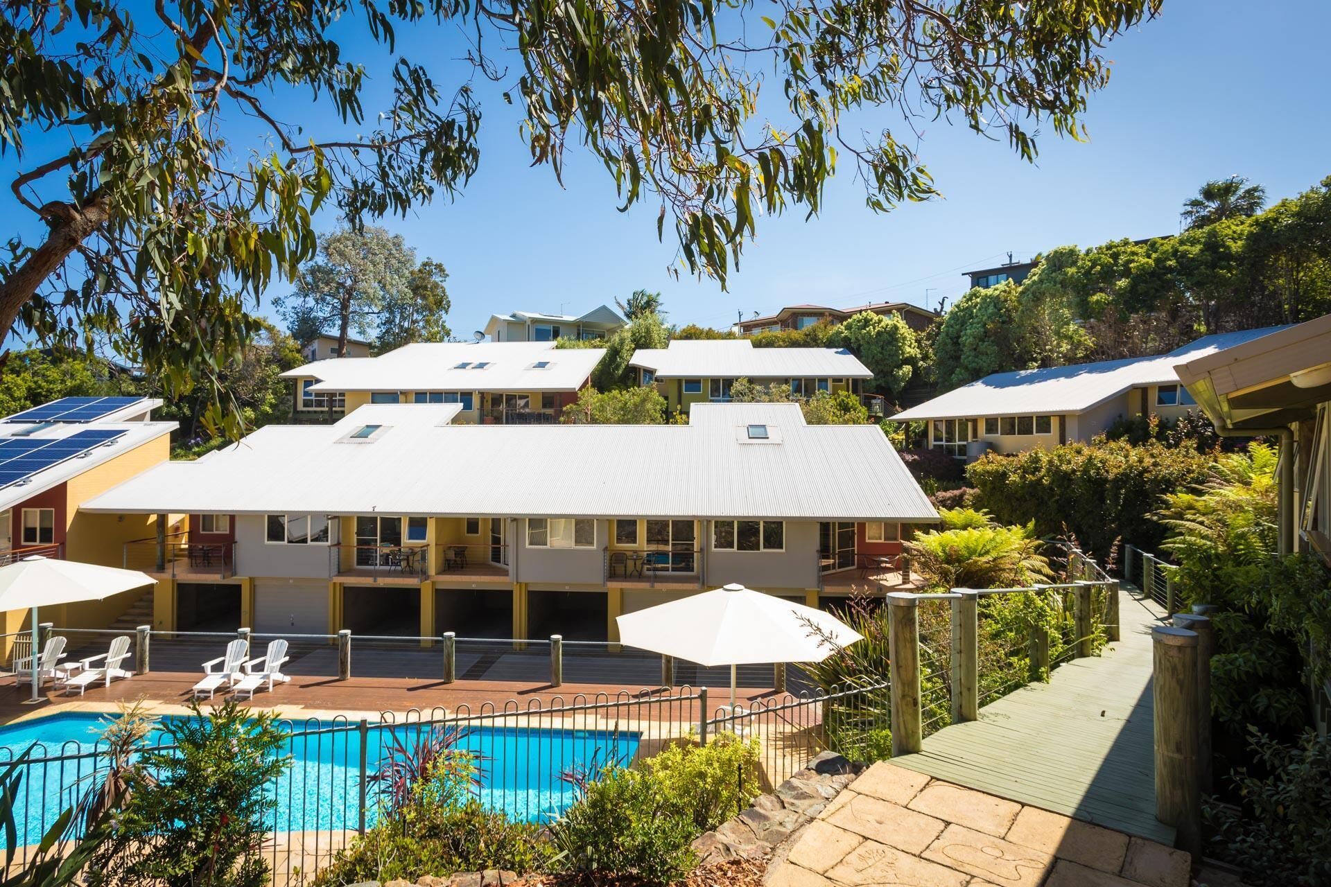 A residential area with a swimming pool, multiple houses, and solar panels.
