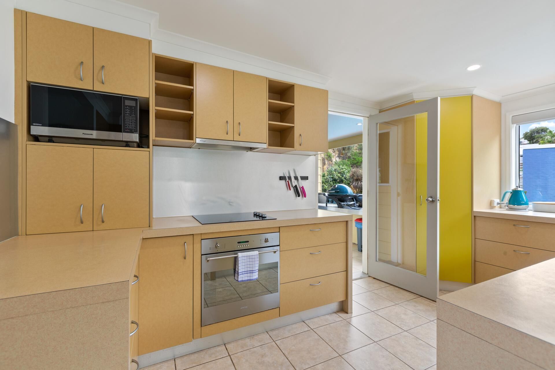 A modern kitchen with wooden cabinets, a built-in oven, and a microwave.