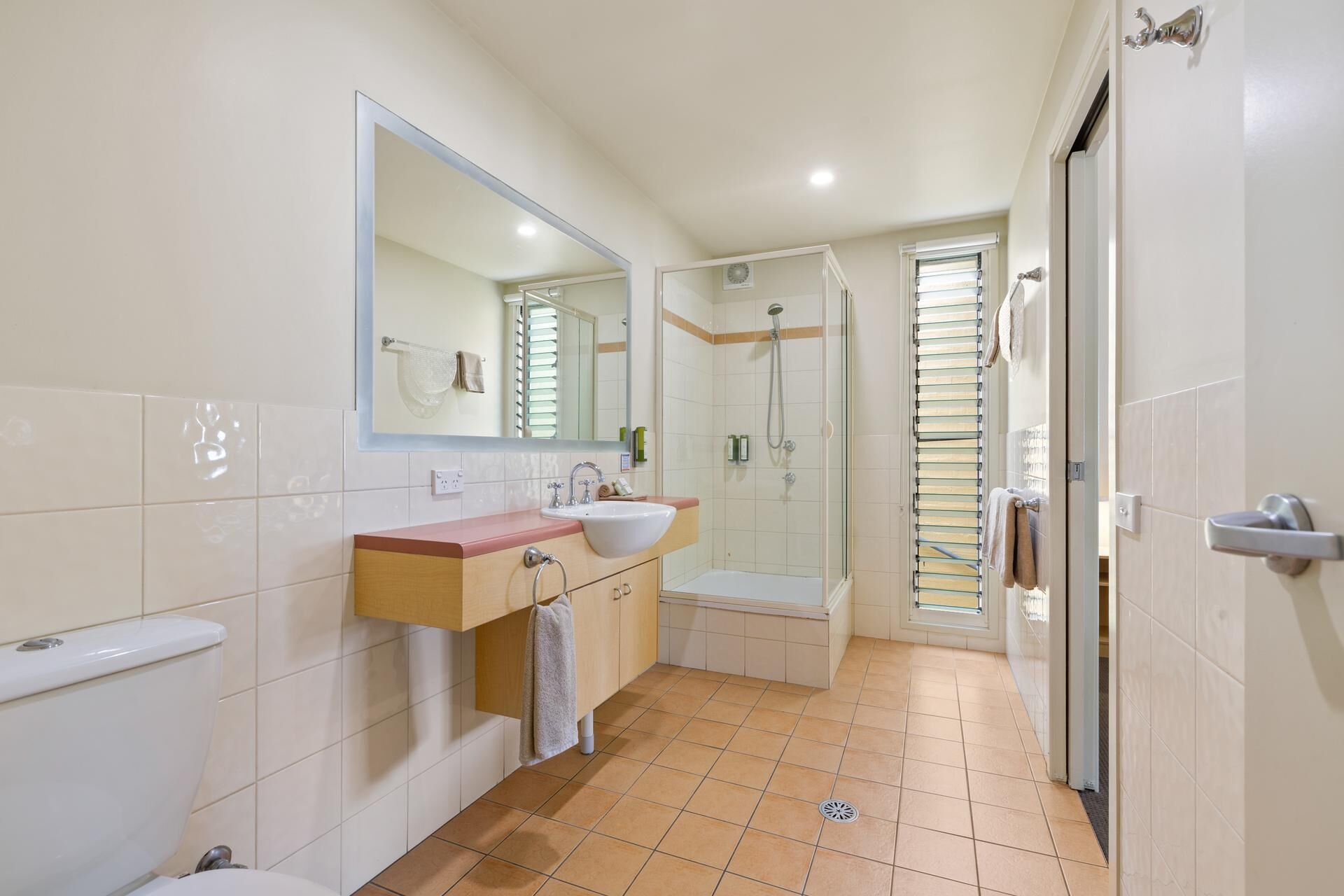 Een moderne badkamer met een dubbele wastafel, een grote spiegel, een douche en een toilet.