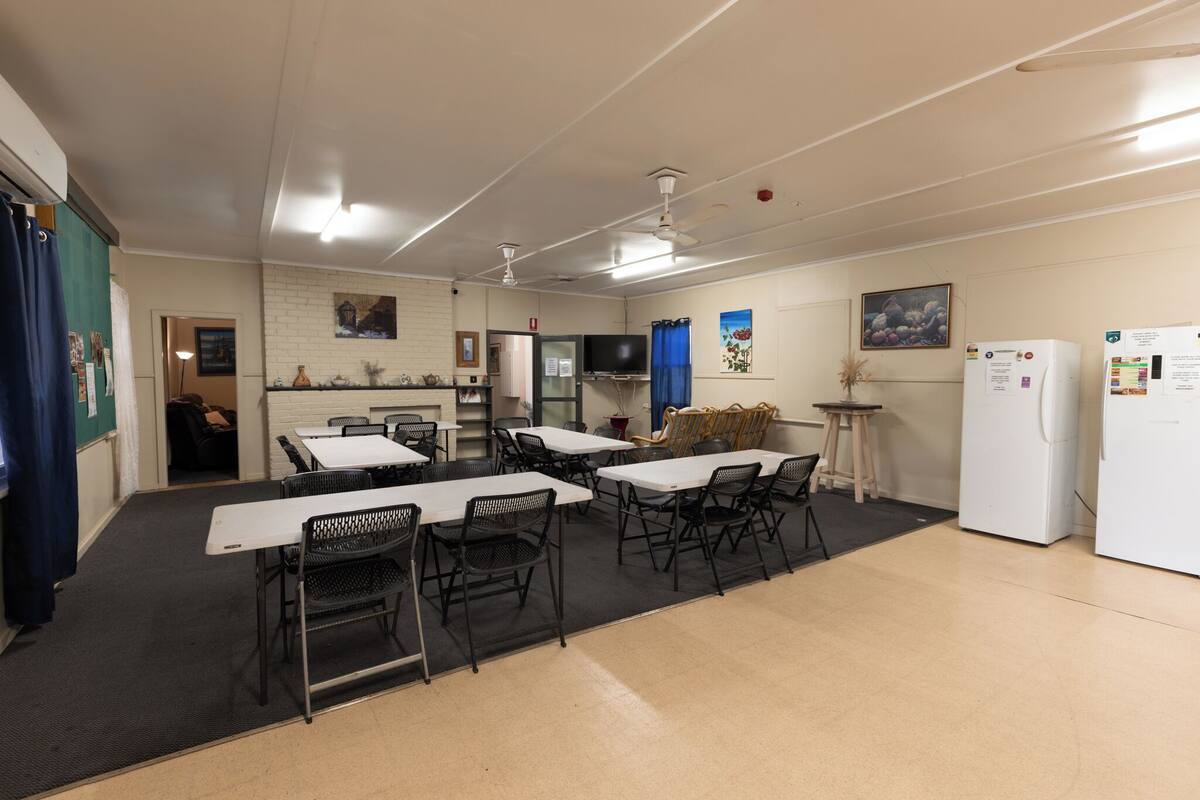 Un espace repas avec des tables et des chaises, un téléviseur et un réfrigérateur.