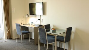 A hotel room with a desk, two chairs, a television, and a small table with a bowl. - Hawera Central Motor Lodge (Hawera)