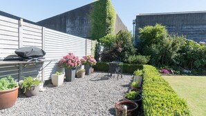 A patio area with a grill, seating, and potted plants. - Hawera Central Motor Lodge (Hawera)
