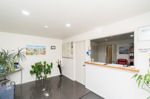 Un área de recepción con un escritorio, sillas, plantas y un mapa en la pared.