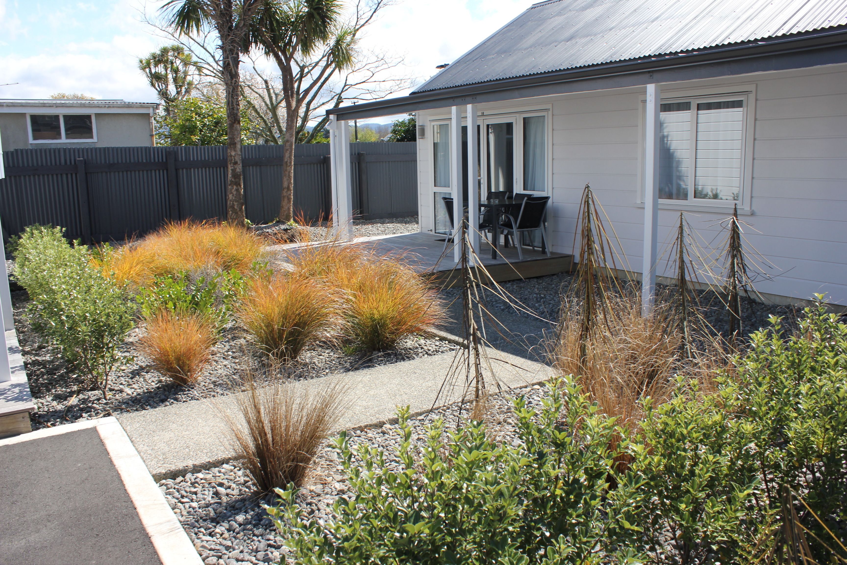 A house with a covered patio, a fenced backyard, and various plants.