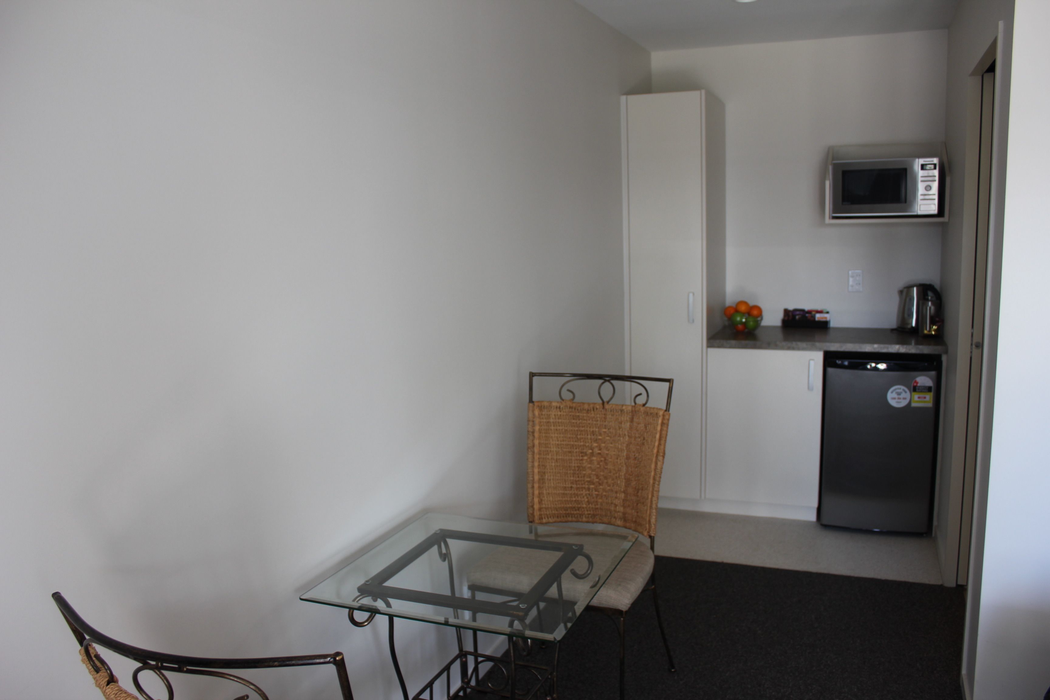 A compact kitchen with a microwave, refrigerator, and a small table with a chair.