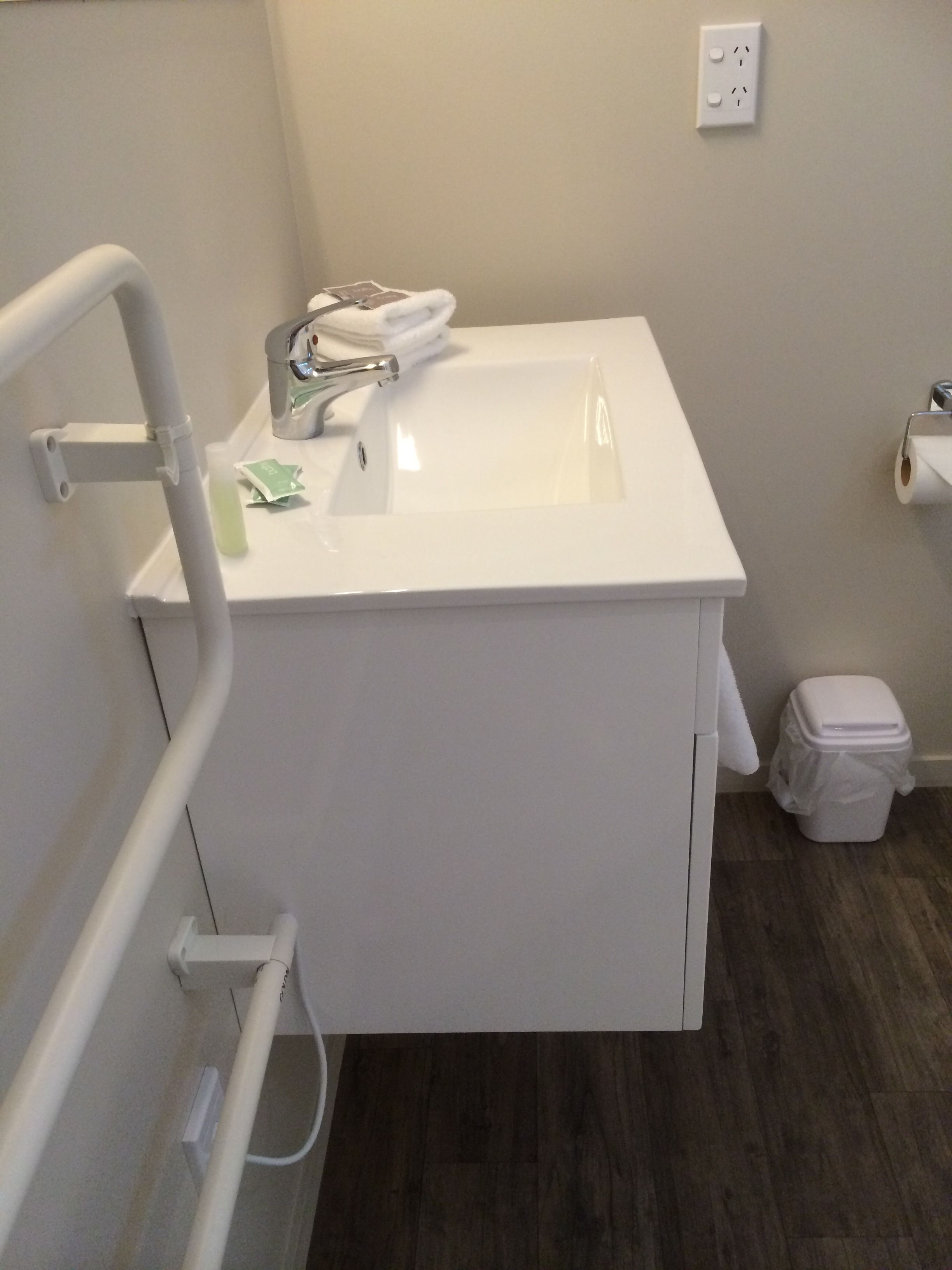 A bathroom with a white sink, a mirror, a towel rack, and a toilet.