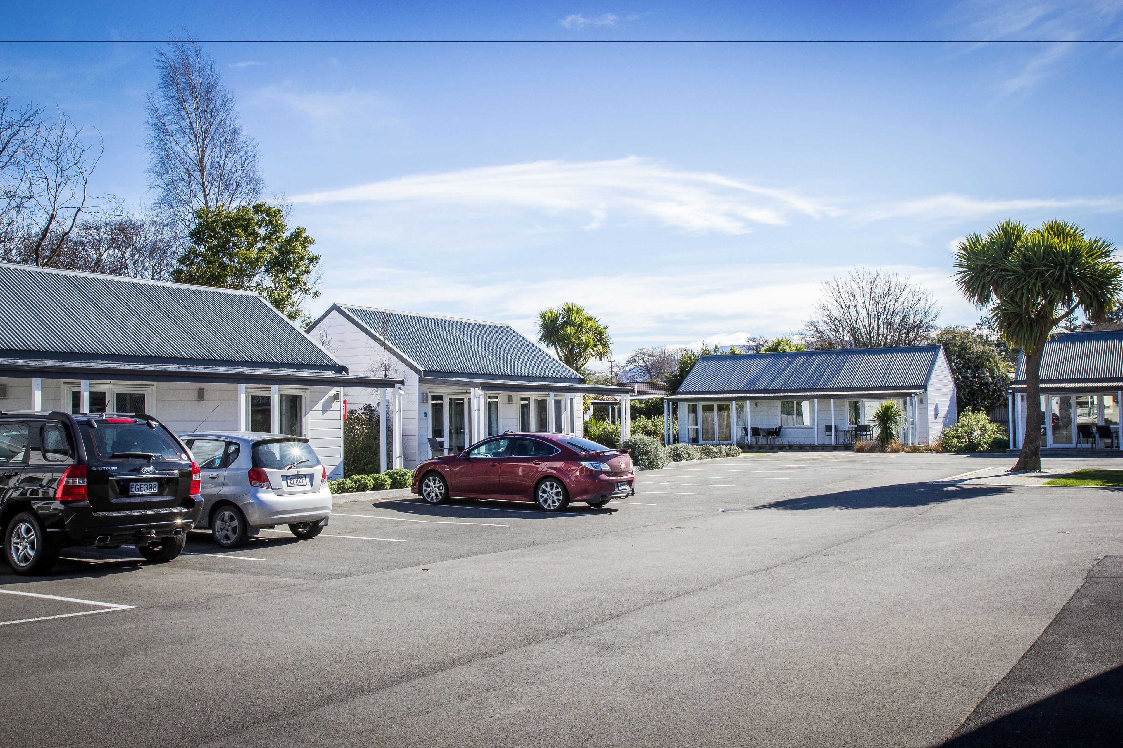 A parking lot with several cars, including a red sedan and a black SUV.
