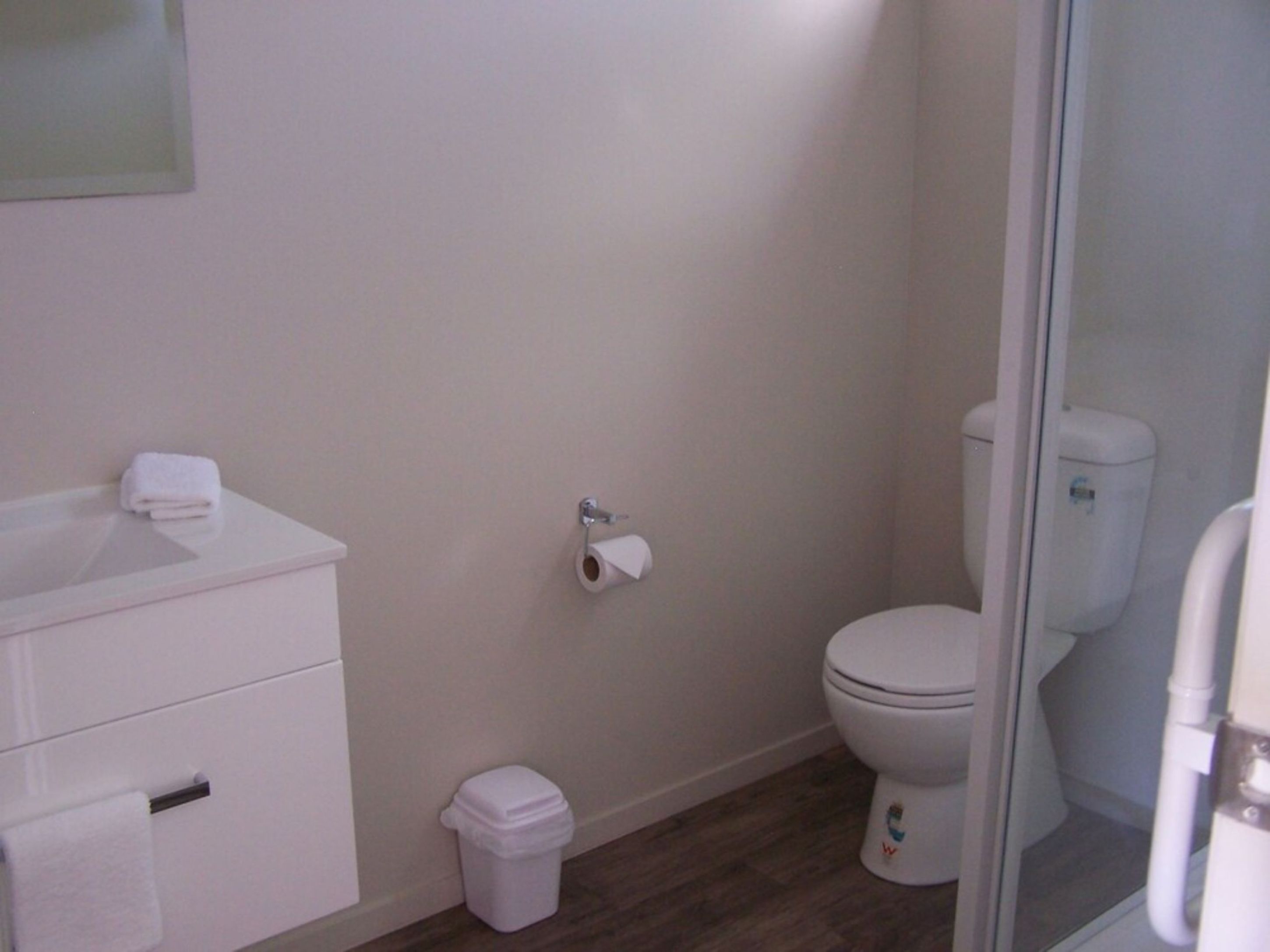 Een badkamer met een wit wastafel, toilet en prullenbak.
