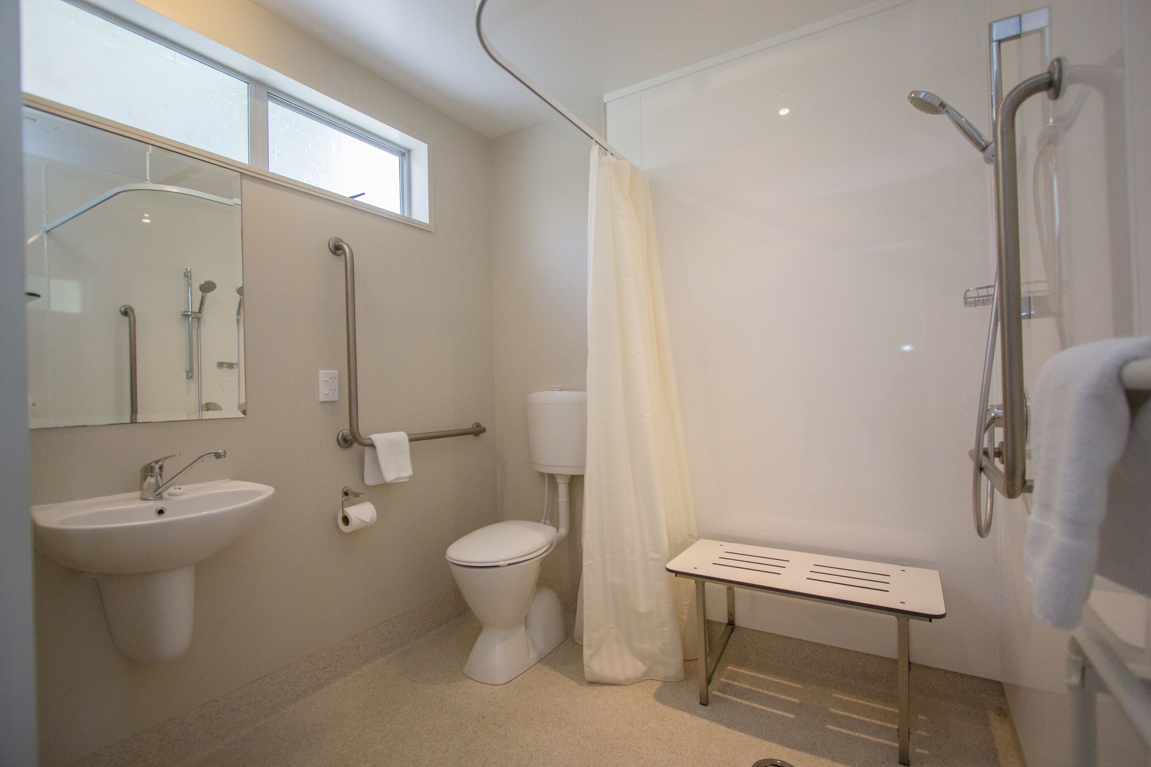 Une salle de bain avec un lavabo, des toilettes, une douche et une fenêtre.