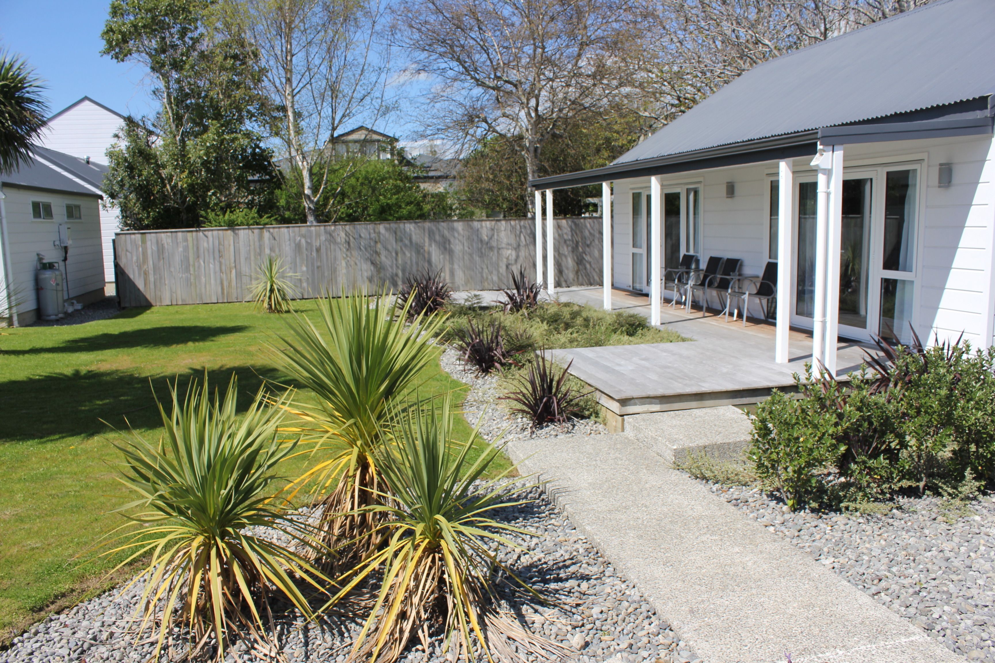 A residential backyard with a patio, a wooden fence, and various plants.