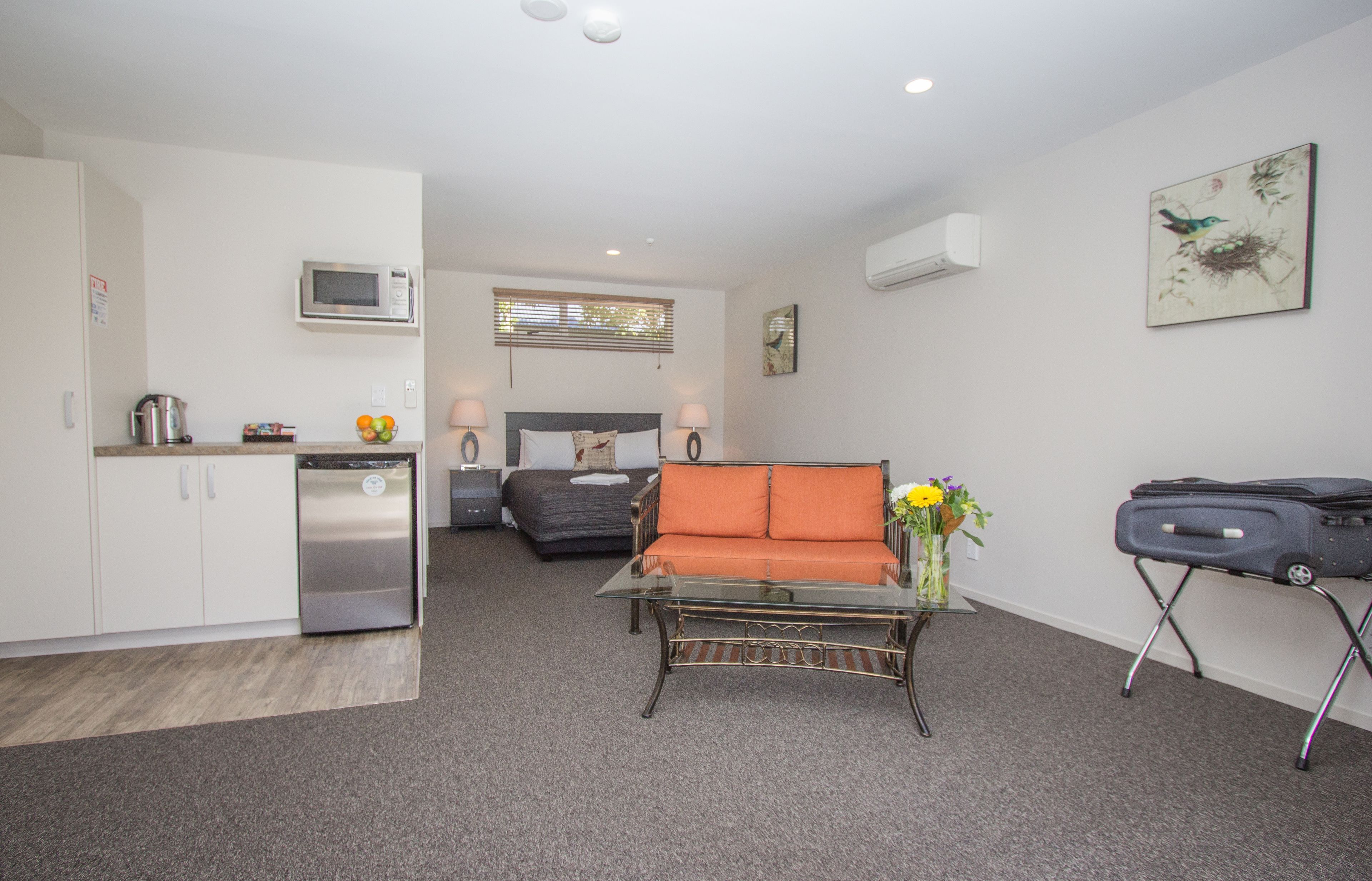 A compact living space with a kitchenette, a sofa, a small table, and a bed.