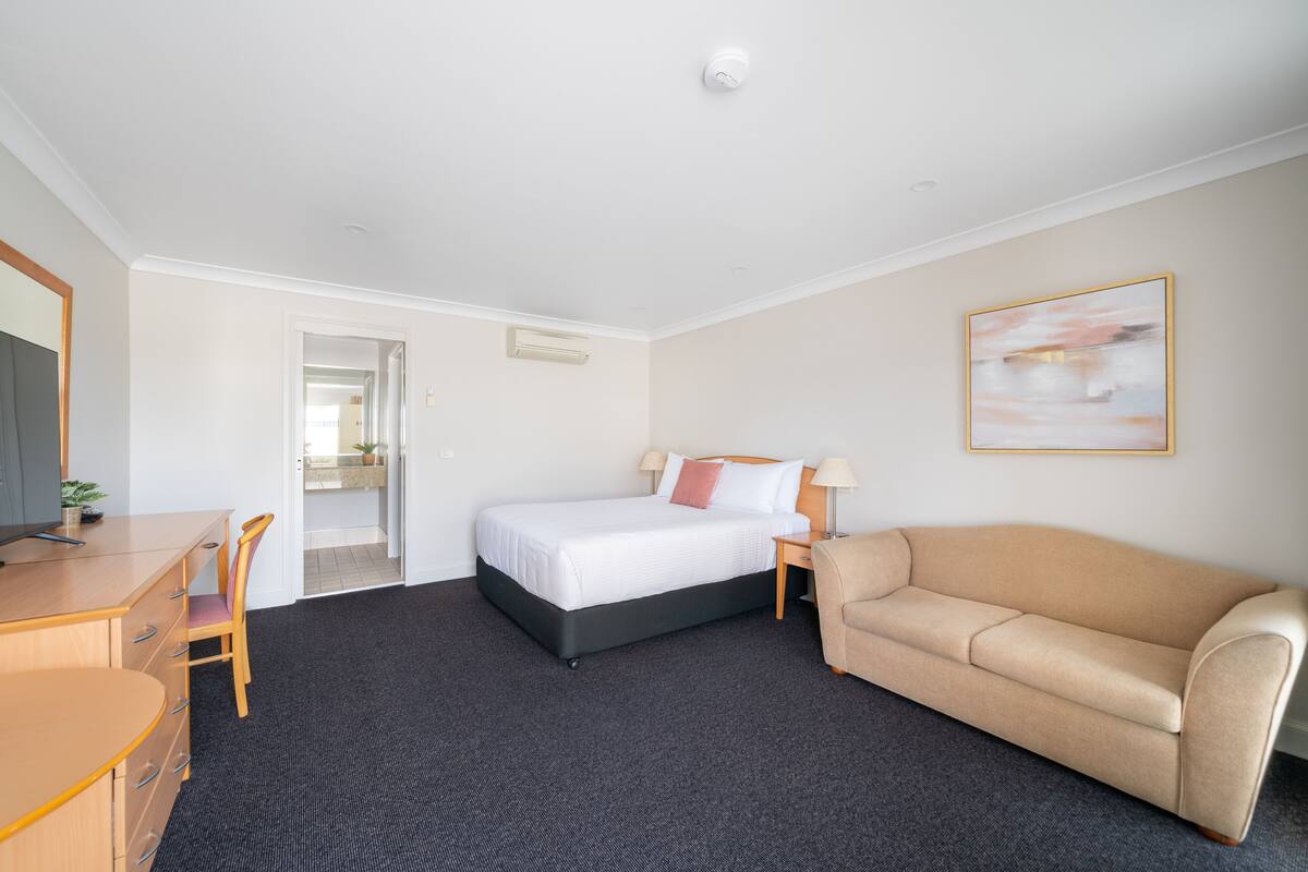 A hotel room with a bed, a sofa, a desk, and a chair.