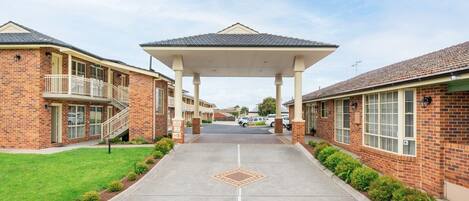 A covered walkway leading to a building with a tiled roof and brick walls.