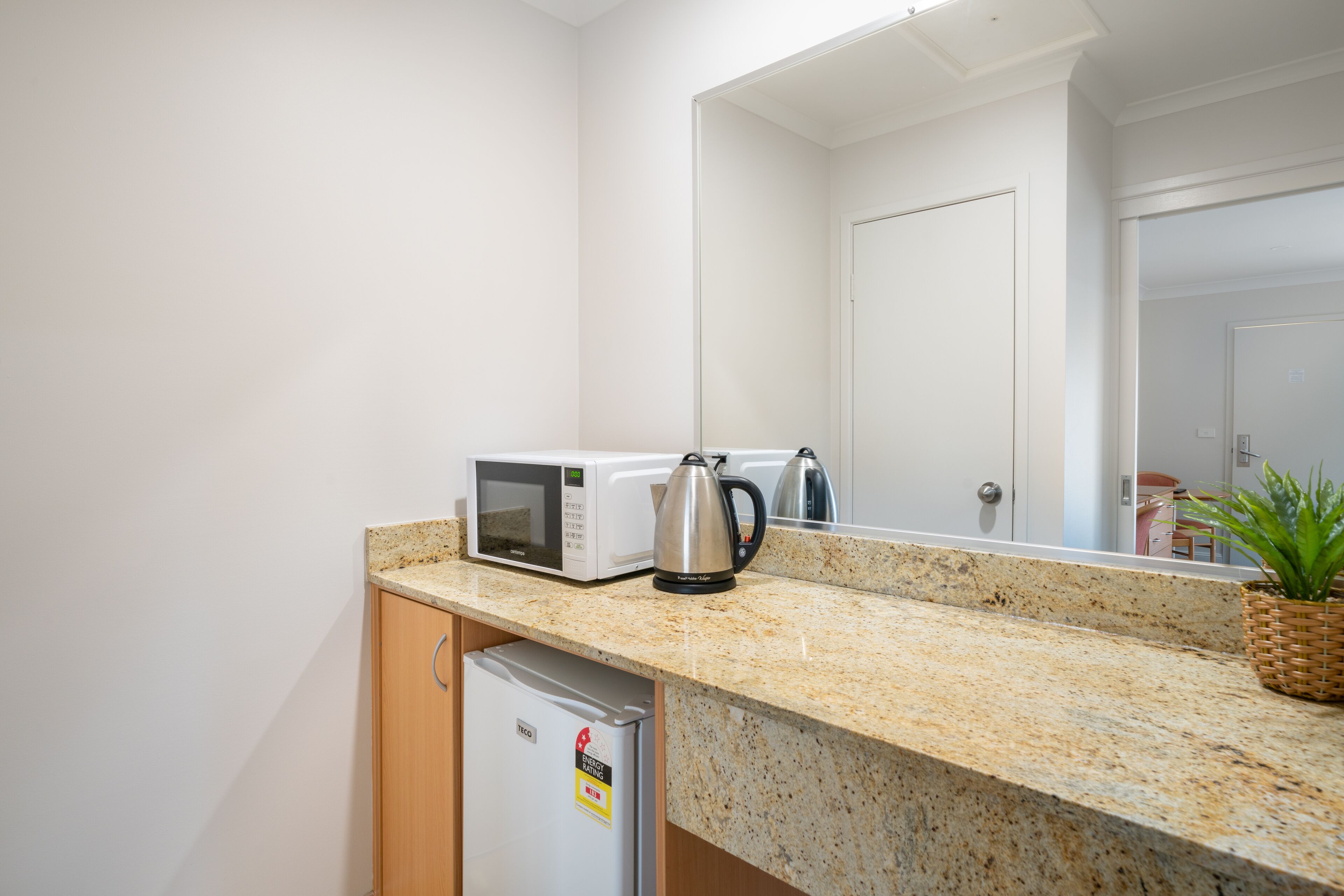 A kitchenette with a microwave, kettle, and a small refrigerator.