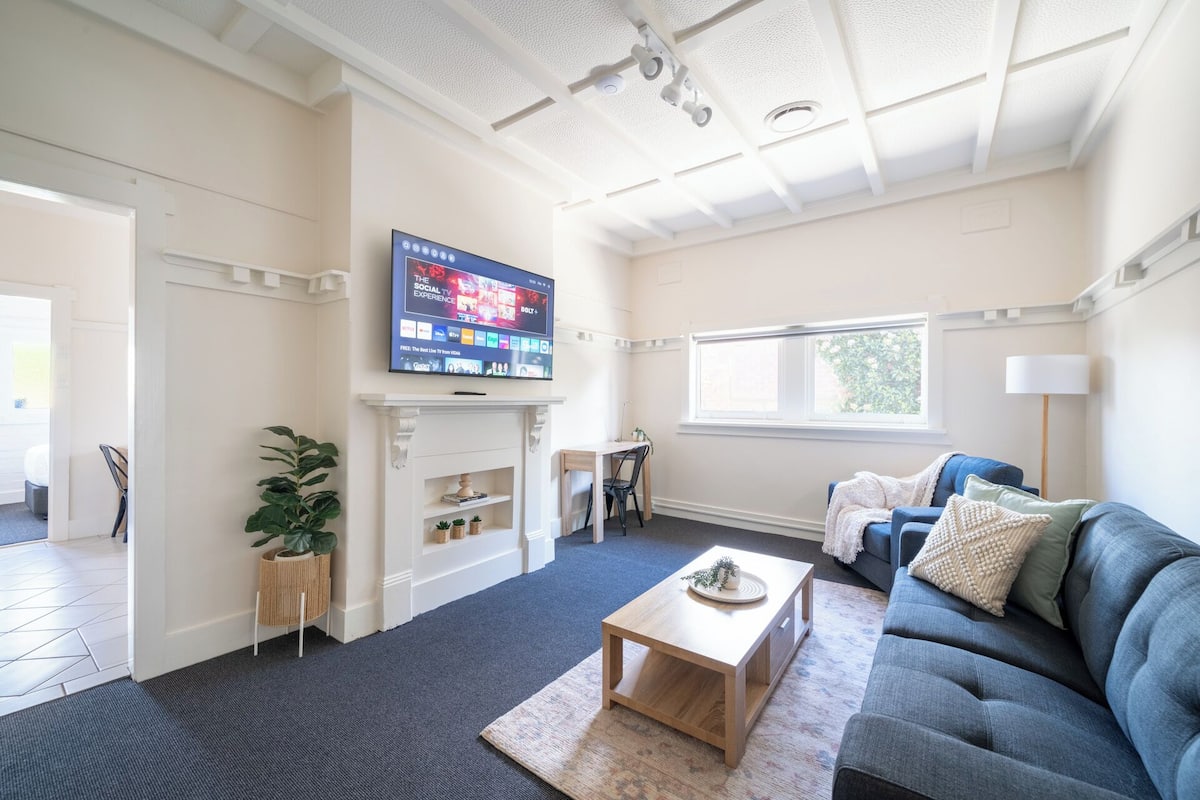 A living room with a TV mounted on the wall, a fireplace, a sofa, and a coffee table.