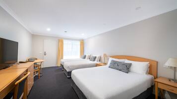 A hotel room with two beds, a desk, a chair, a TV, and a window with curtains.
