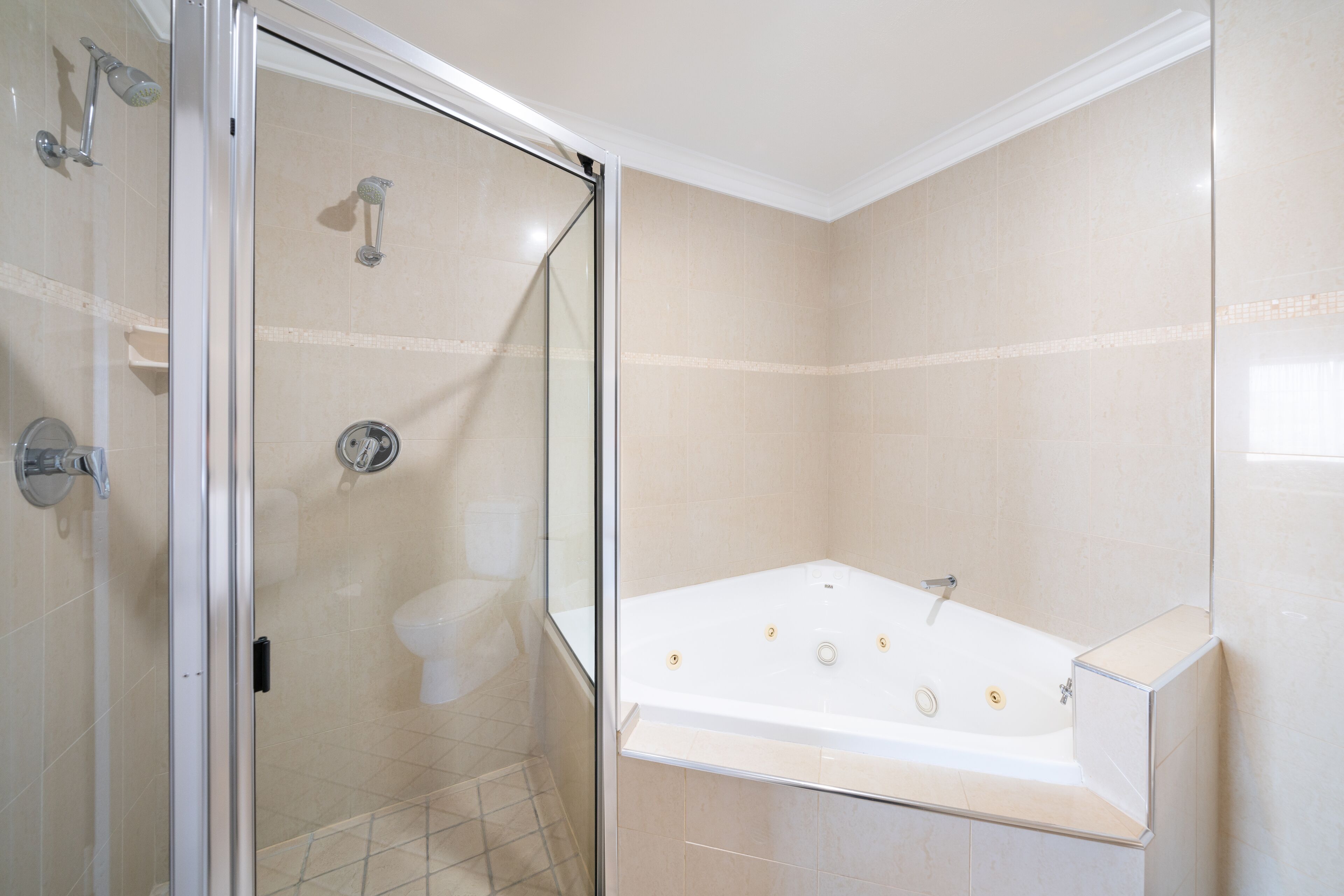 Un baño moderno con ducha de vidrio, una bañera independiente y un inodoro.