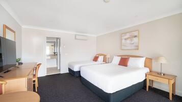 A hotel room with two beds, a desk, a chair, a TV, and a painting on the wall.