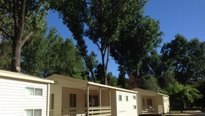 A row of mobile homes with attached porches, set in a wooded area. - Mt Buffalo Caravan Park (Porepunkah)
