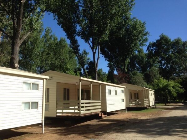 A row of mobile homes with attached porches, set in a wooded area.