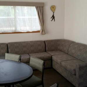 A room with a sectional sofa, a round table, and a wall clock.