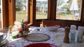 A dining table set with a floral centerpiece, a woven placemat, and salt and pepper shakers. - Melville House (Lismore)