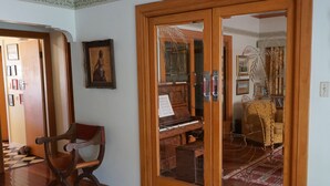 A room with a piano, a wooden chair, a framed picture on the wall, and a patterned rug. - Melville House (Lismore)