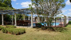A covered patio area with a pool, surrounded by greenery and a clear sky. - Melville House (Lismore)