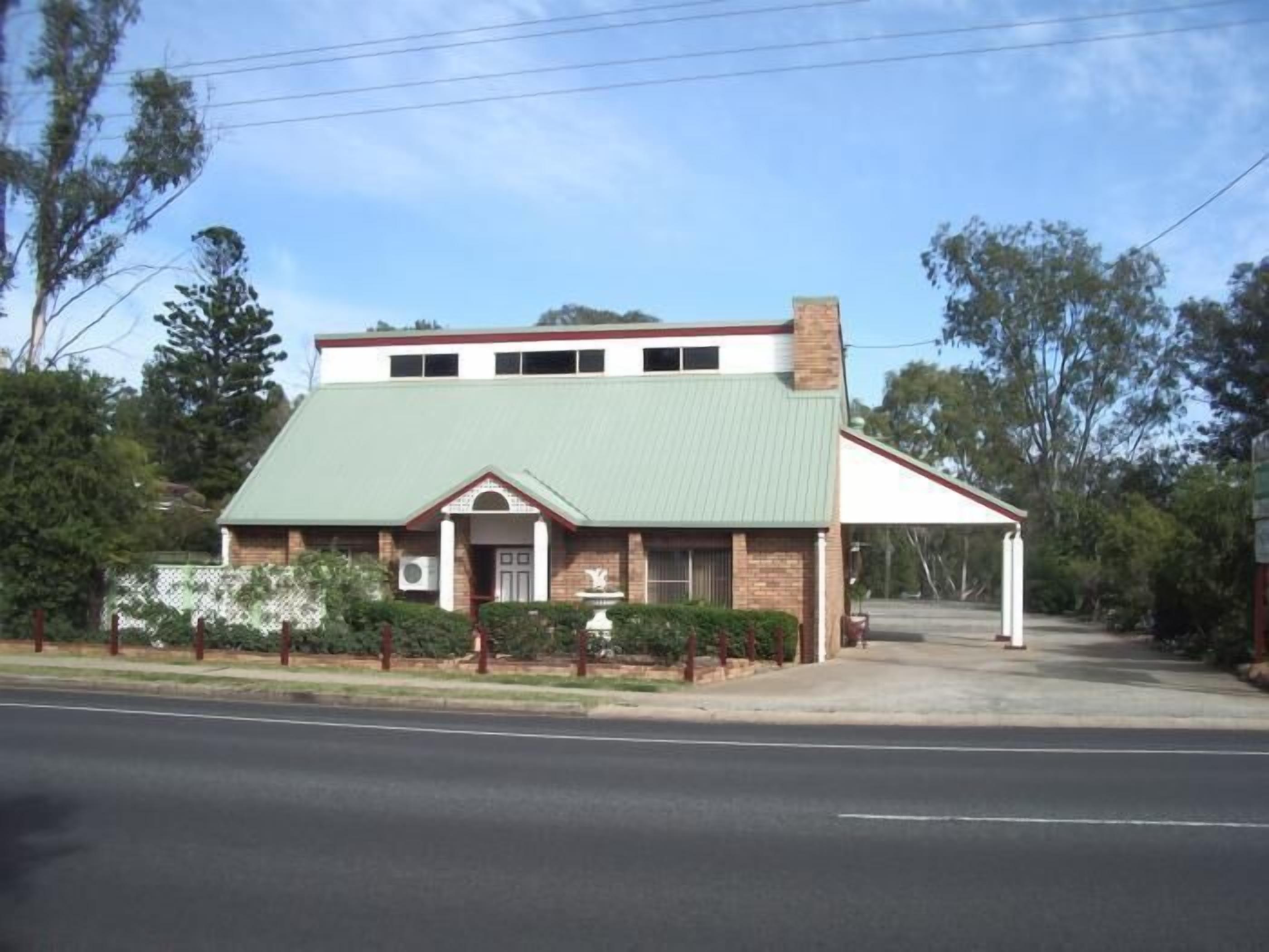 A two-story building with a green roof, a brick facade, and a small porch.