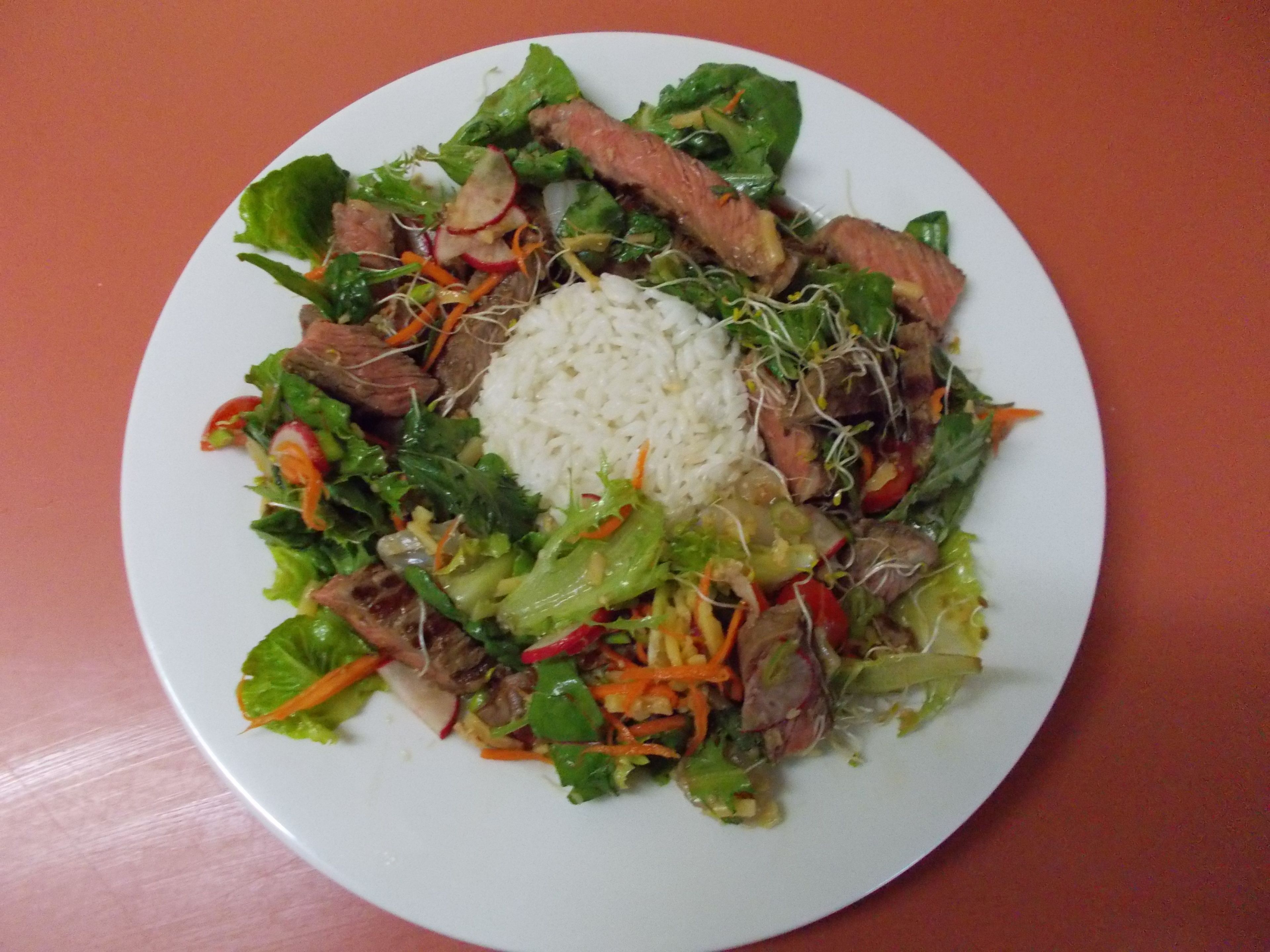 A plate of food with beef, rice, and vegetables.