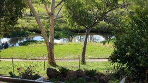 A garden with a pond, trees, and a white outdoor table. - Park House Motor Inn (Oakey)