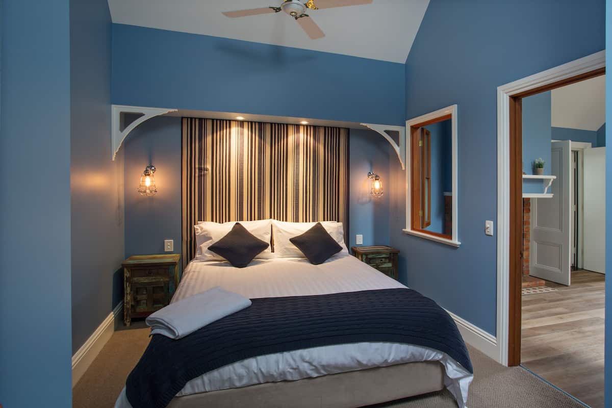 A bedroom with a bed, bedside tables, a ceiling fan, and a mirror.