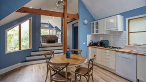 A modern kitchen with white cabinets, a wooden dining table, and a view of the outdoors. - Oak Tree Lodge (Rhyll)